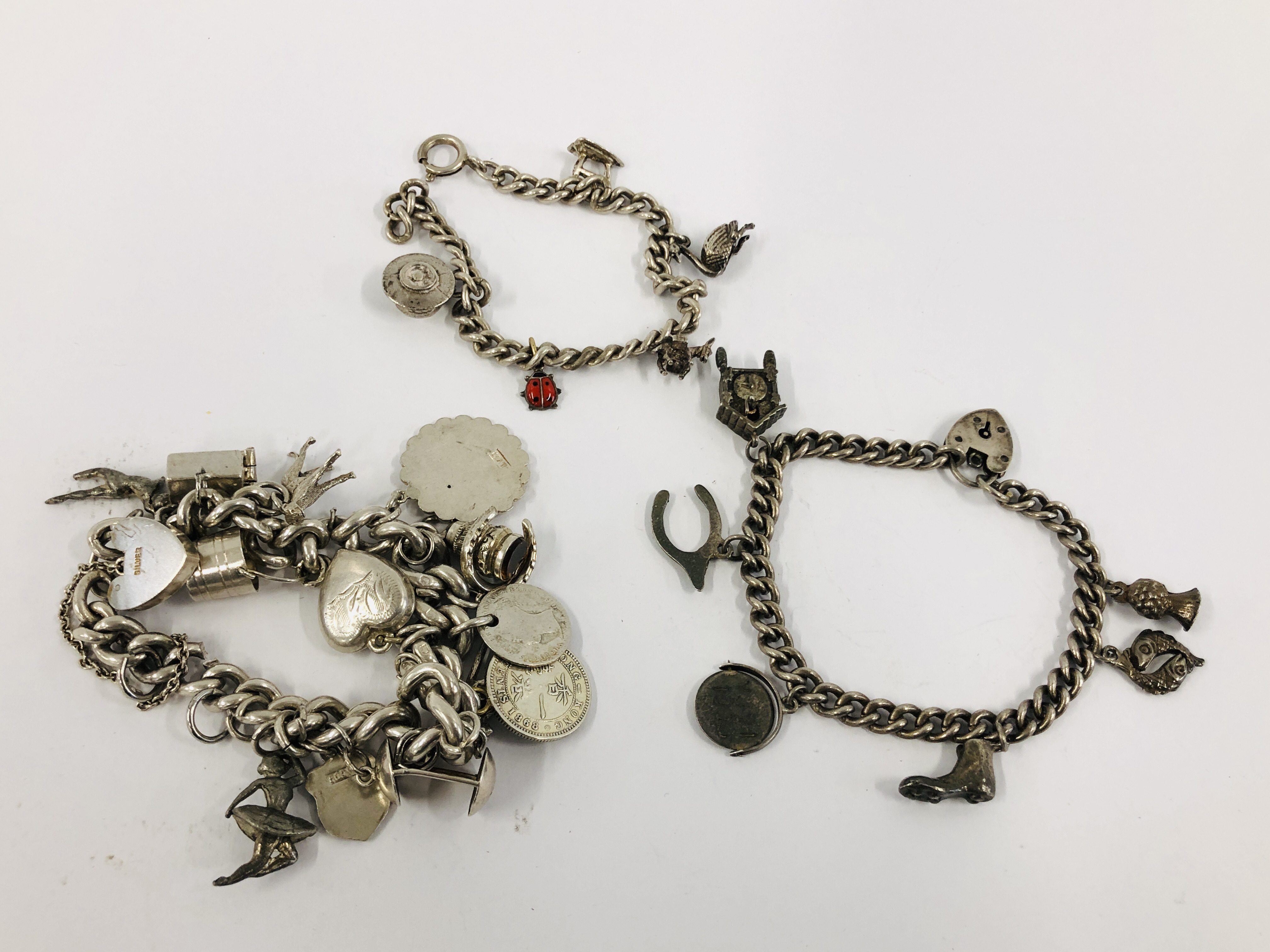 THREE VINTAGE SILVER CHARM BRACELETS TO INCLUDE VARIOUS SILVER AND WHITE METAL CHARMS.