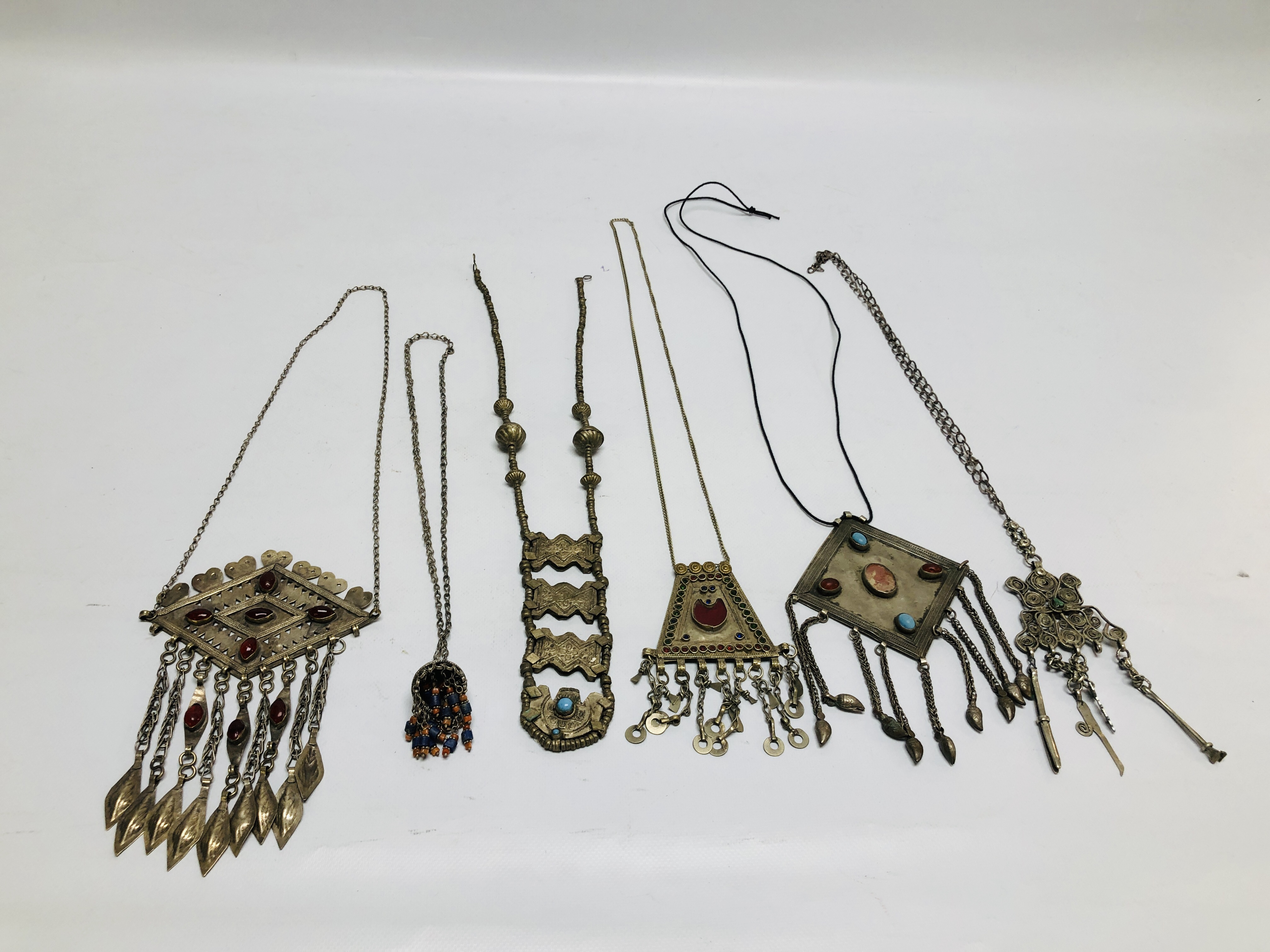 A GROUP OF 6 ASSORTED EASTERN STYLE WHITE METAL PENDANT NECKLACES TO INCLUDE STONE SET EXAMPLES.