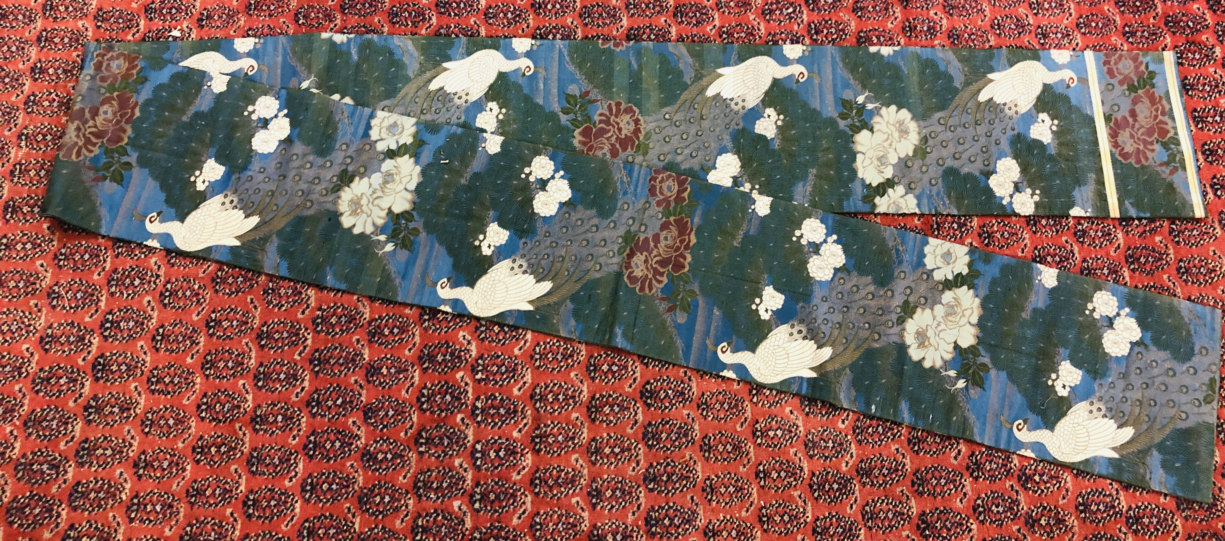 A CHINESE SILK "OBI" ON A DARK BLUE FIELD DECORATED WITH PEACOCKS AND FLOWERS.