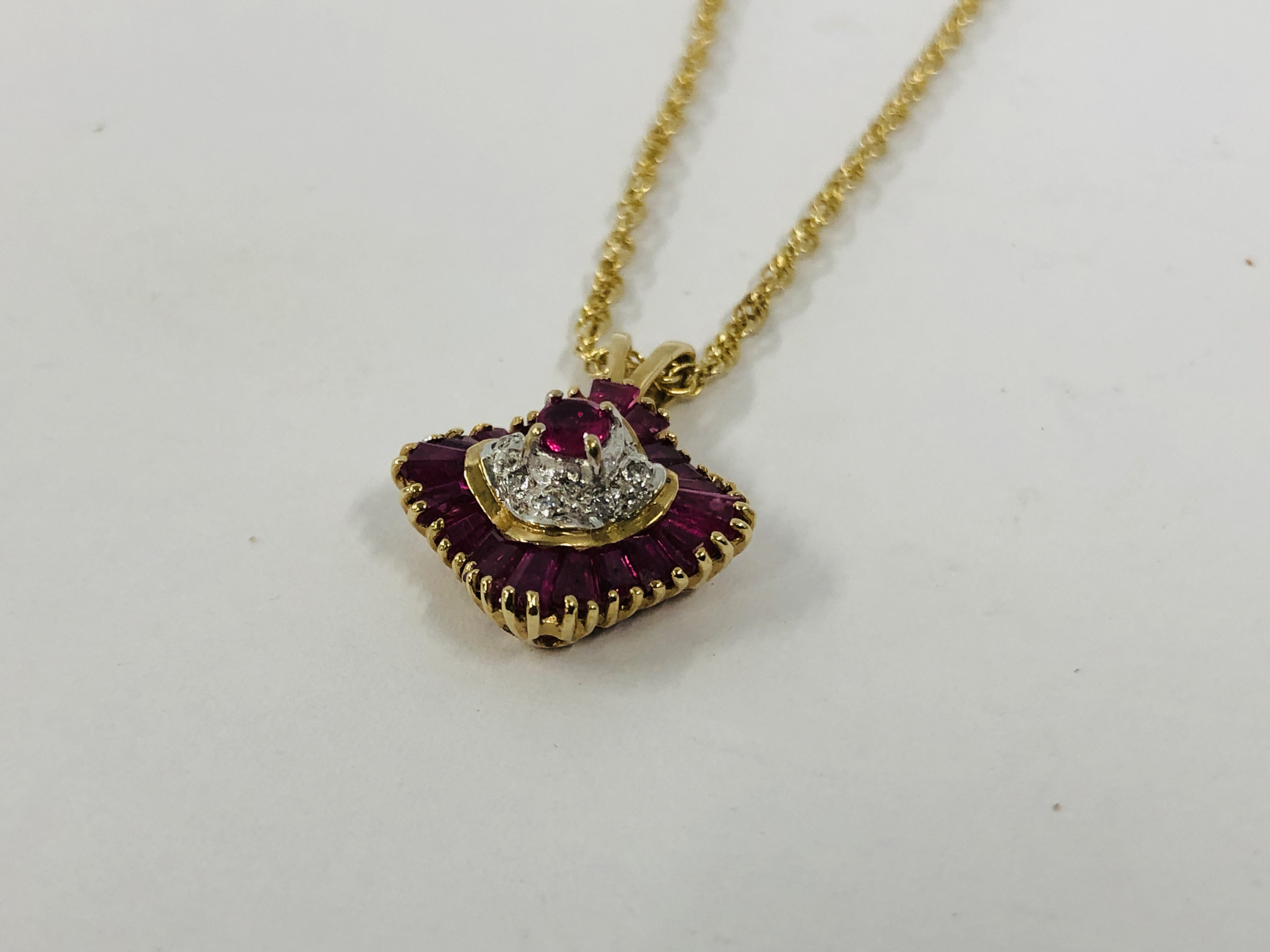 AN ORNATE PENDANT SET WITH MAINLY PINK STONE ON A FINE INTERTWINED 9CT GOLD CHAIN.