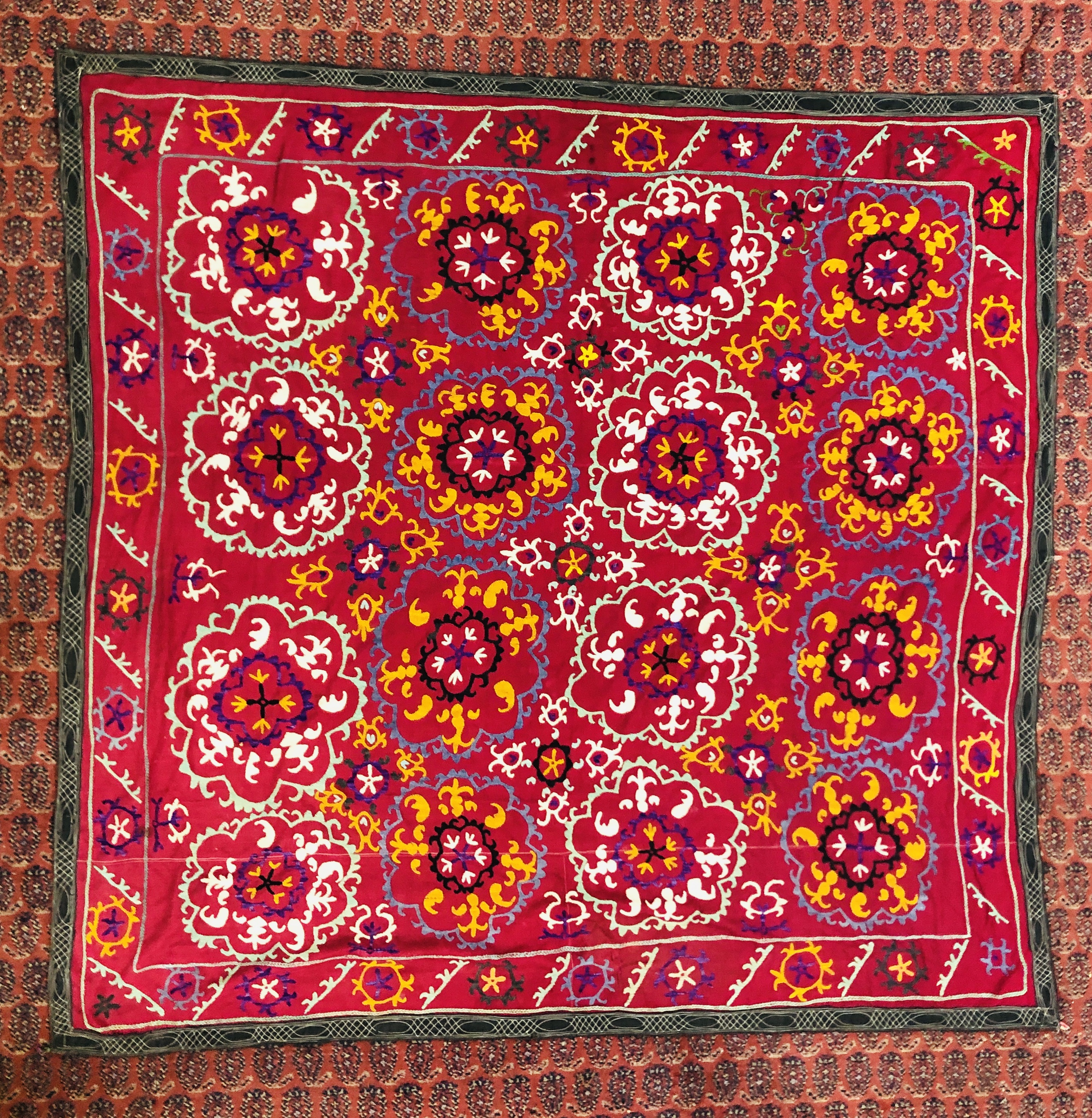 A SUZANI EMBROIDERED ON A PLUM FIELD, 180CM X 171CM.