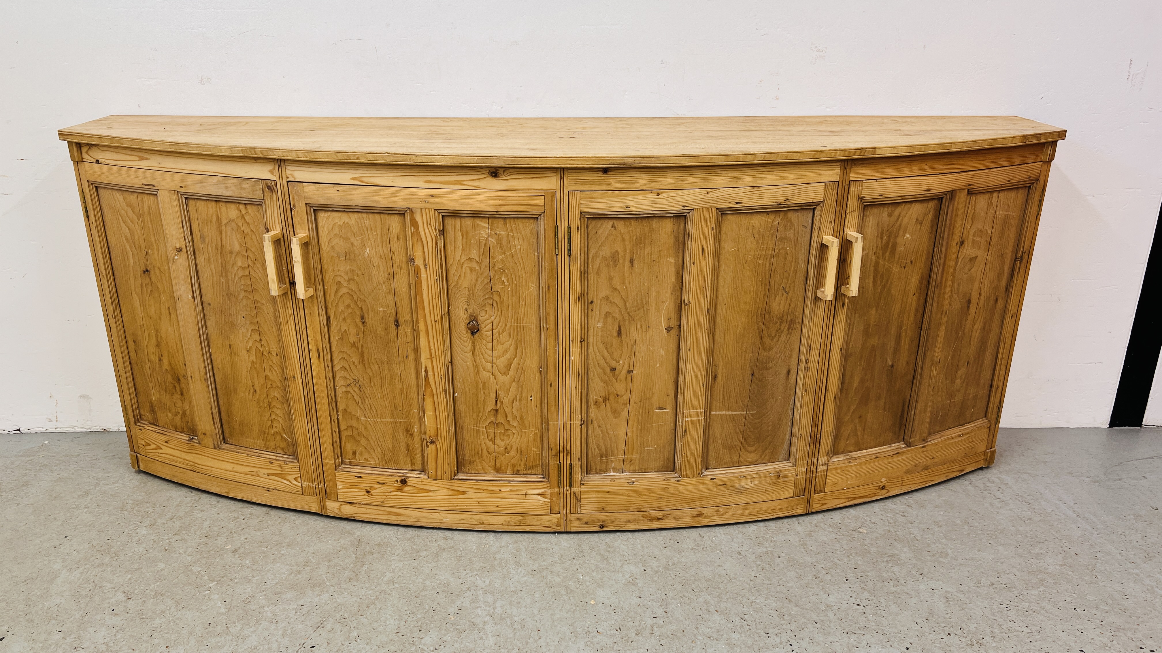 A LARGE SOLID PINE BOW FRONTED 4 DOOR SIDE CABINET W 246CM. X D 61CM. X H 96CM.