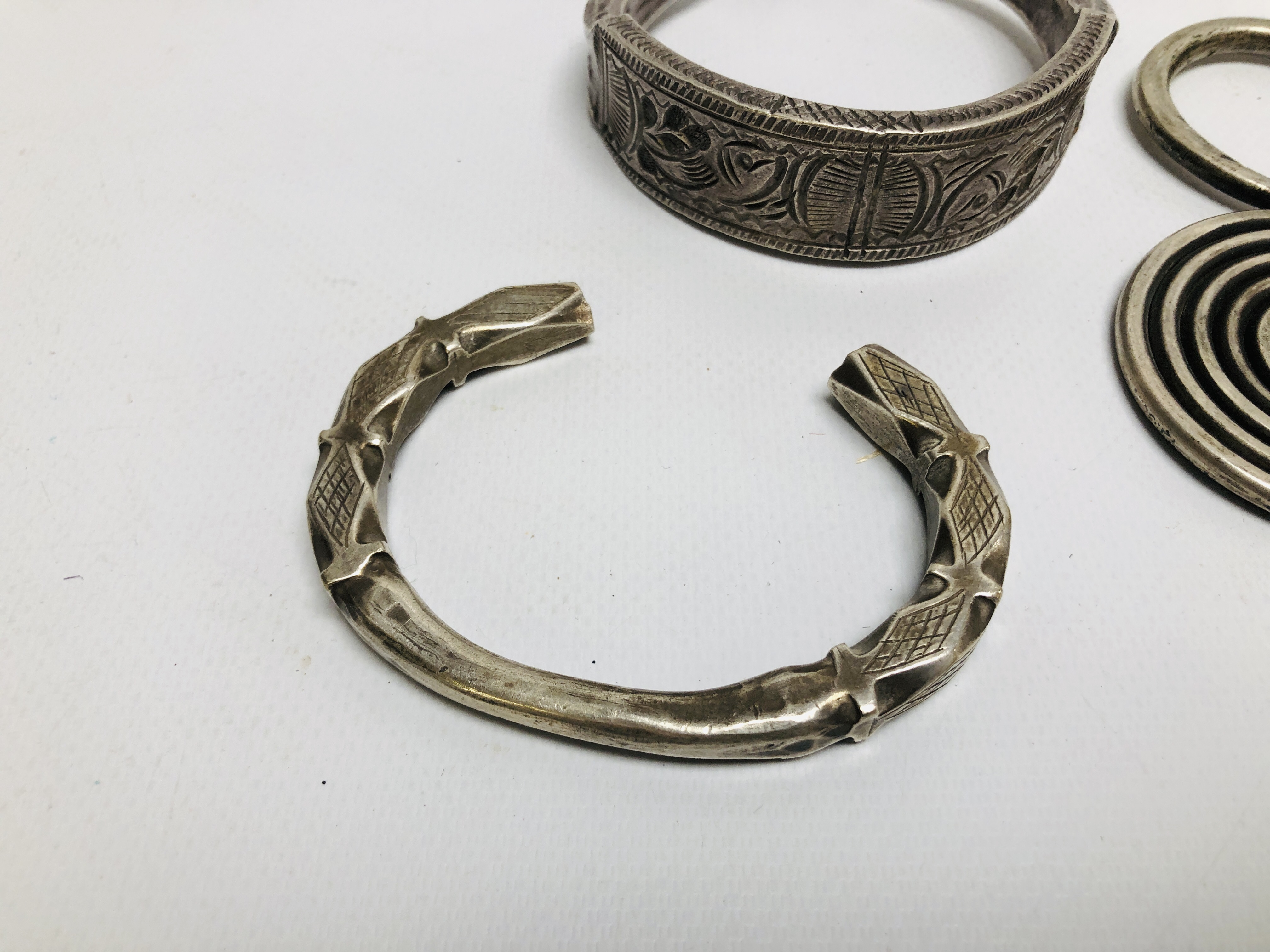 THREE EASTERN TRIBAL STYLE WHITE METAL CUFF BRACELETS OF HAMMERED DESIGN ALONG WITH A FURTHER WHITE - Image 2 of 5