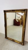 A LARGE HEAVILY DETAILED GILT FRAMED WALL MIRROR WITH BEVELLED GLASS.