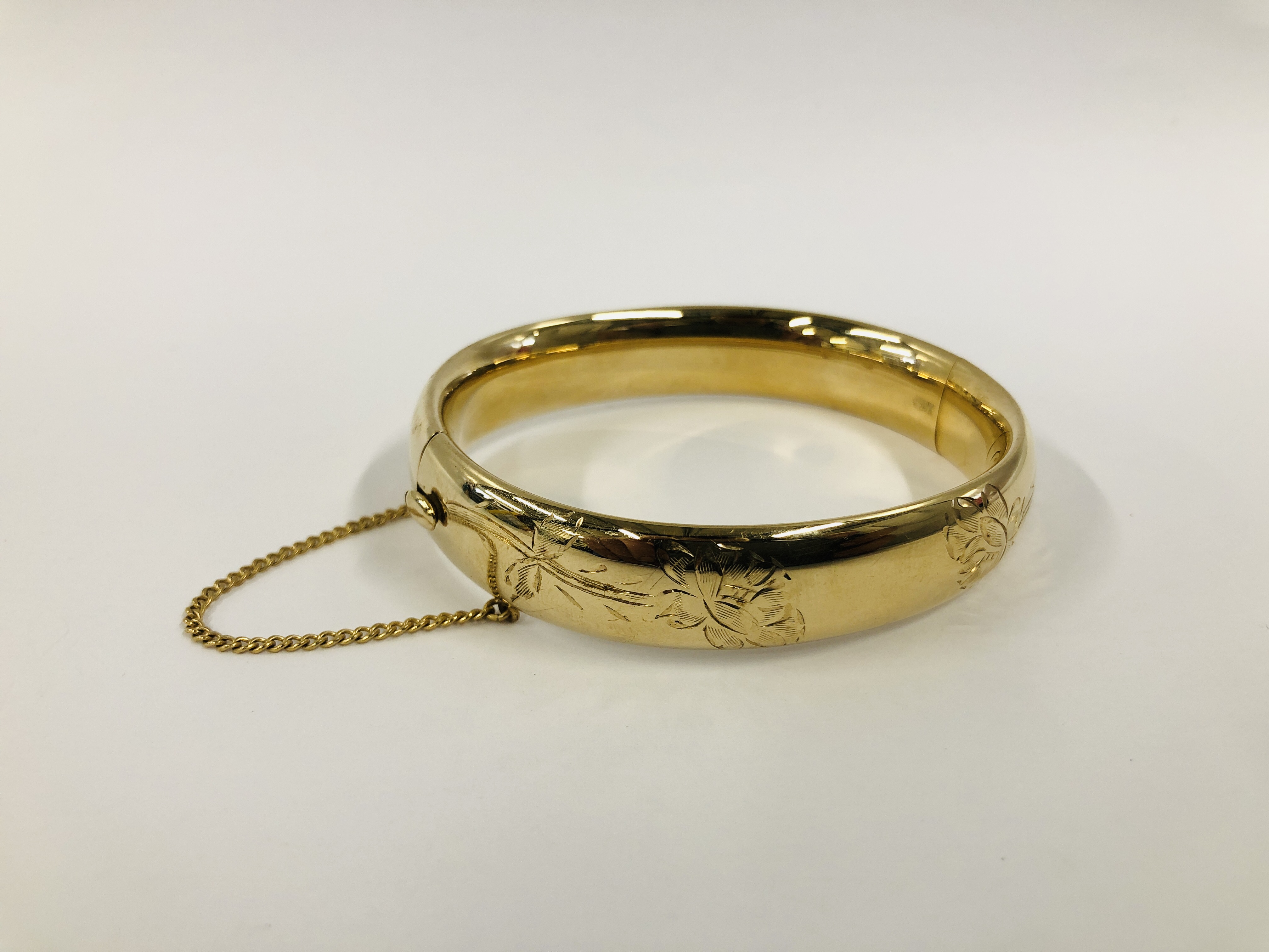 A GOLD FILLED HINGED BANGLE WITH CHASED DECORATION