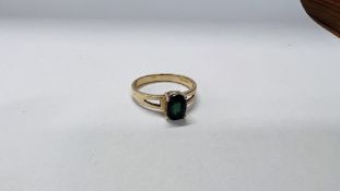 A LADIES 9CT GOLD RING SET WITH SINGLE OVAL GREEN STONE AND OPEN SHOULDERS.