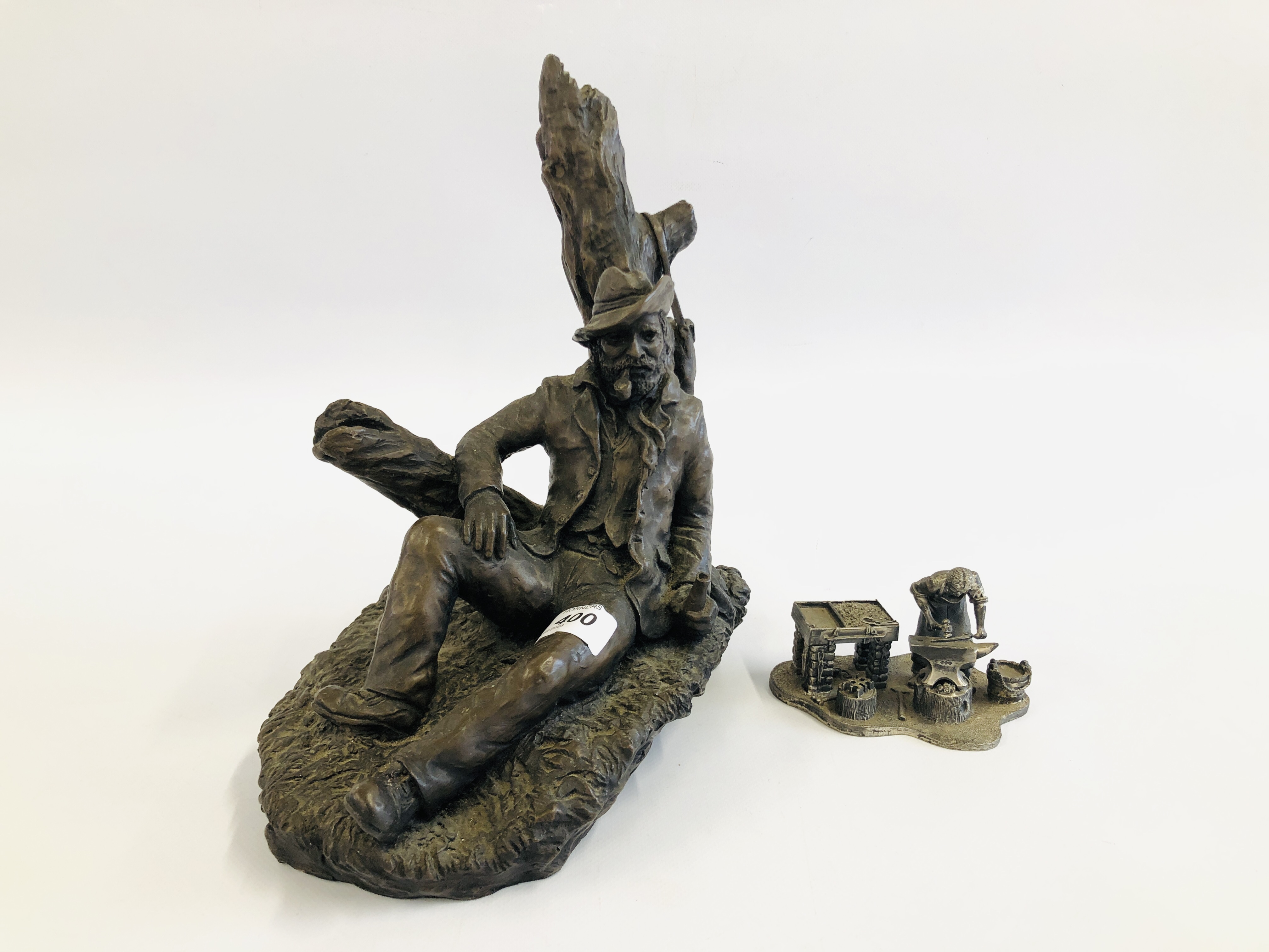 A MODERN BRONZED SCULPTURE OF A SEATED GENTLEMAN AGAINST A TREE STUMP ALONG WITH "THE LEONARDO