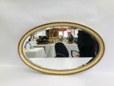 AN ELEGANT OVAL WALL MIRROR WITH BEVELLED PLATE GLASS - HEIGHT 83CM. WIDTH 52CM.