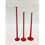 THREE RUBY GLASS LONG STEMMED HOLLOW CANDLESTICKS, THE LARGEST 60CM.