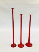 THREE RUBY GLASS LONG STEMMED HOLLOW CANDLESTICKS, THE LARGEST 60CM.