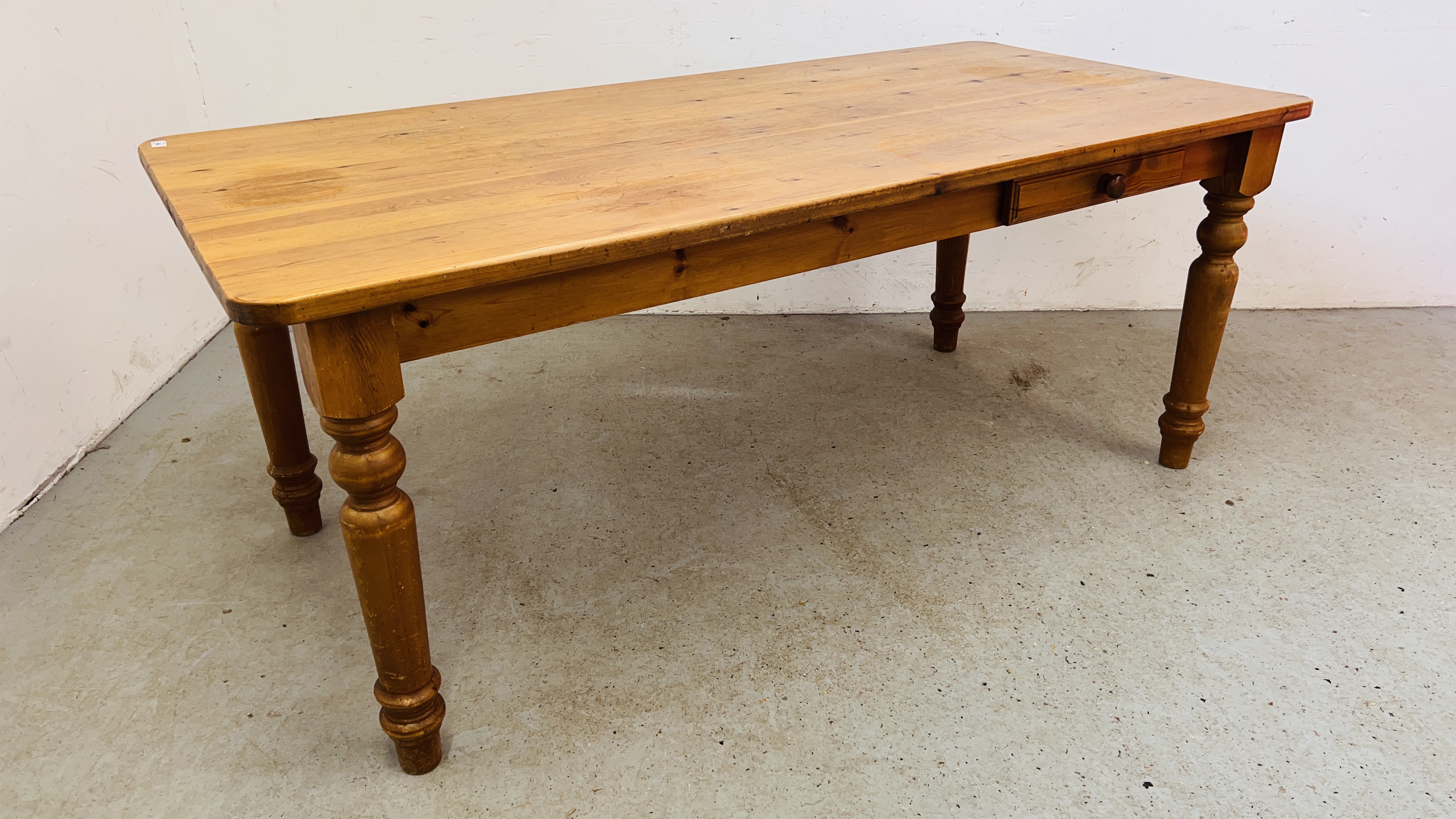 A WAXED PINE KITCHEN TABLE ON TURNED LEGS.