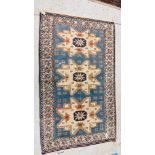 AN EASTERN RUG THE THREE CENTRAL BEIGE SYMMETRICAL DESIGNS ON A BLUE GROUND, 175 X 107CM.