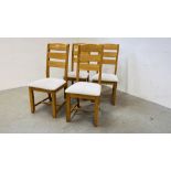 A SET OF FOUR SOLID OAK FRAMED DINING CHAIRS WITH CREAM UPHOLSTERED SEATS.