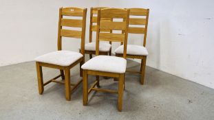 A SET OF FOUR SOLID OAK FRAMED DINING CHAIRS WITH CREAM UPHOLSTERED SEATS.