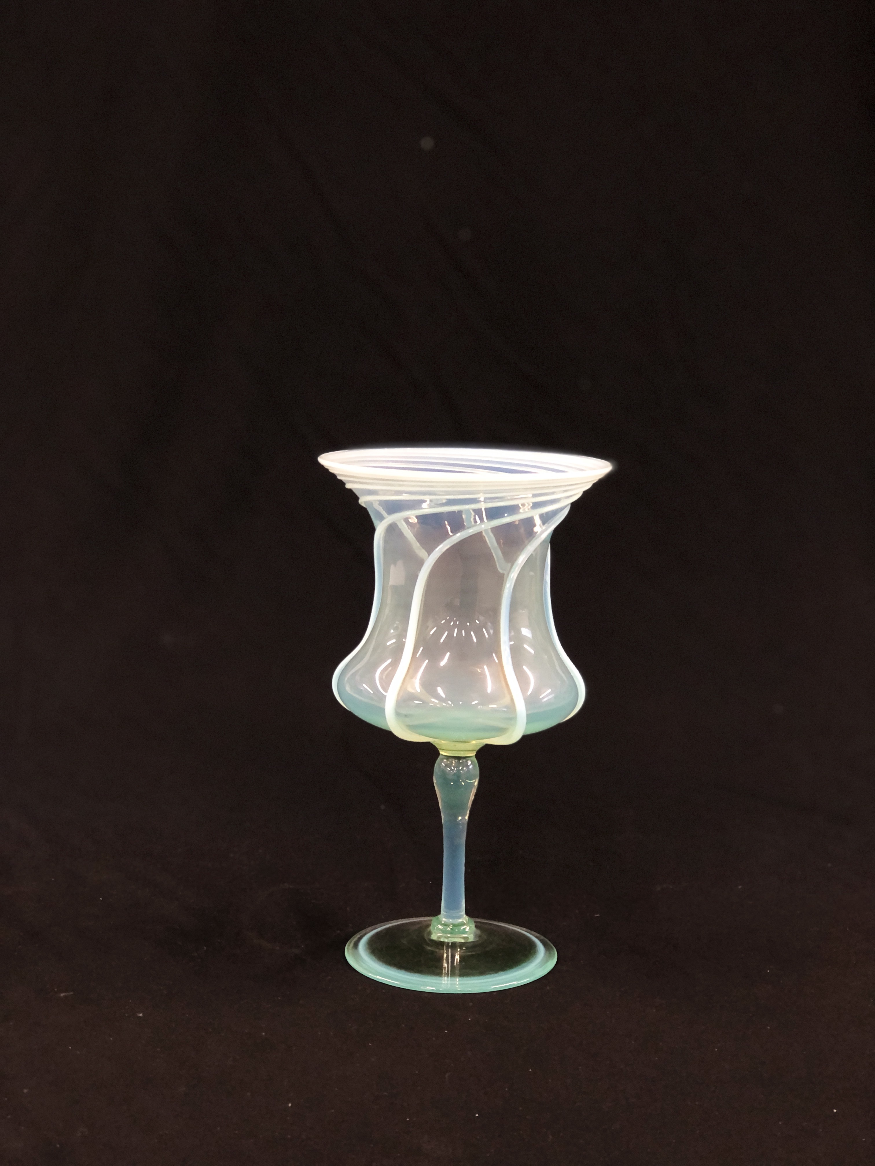 A VENETIAN GOBLET, PALE GREEN WITH SPIRAL OVERLAY ON THE THISTLE SHAPED BOWL, 23CM. HIGH.