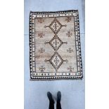 A C20th TRIBAL RUG, THE THREE CENTRAL LOZENGES ON A LIGHT BROWN FIELD,