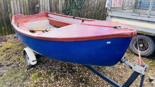 A FIBRE GLASS ROWING DINGY 11FT LONG ON SINGLE AXLE ROAD TRAILER COMPLETE WITH A PAIR OF OARS.