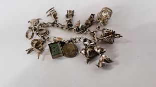 A SILVER CHARM BRACELET WITH APPROX 13 SILVER & WHITE METAL CHARMS.