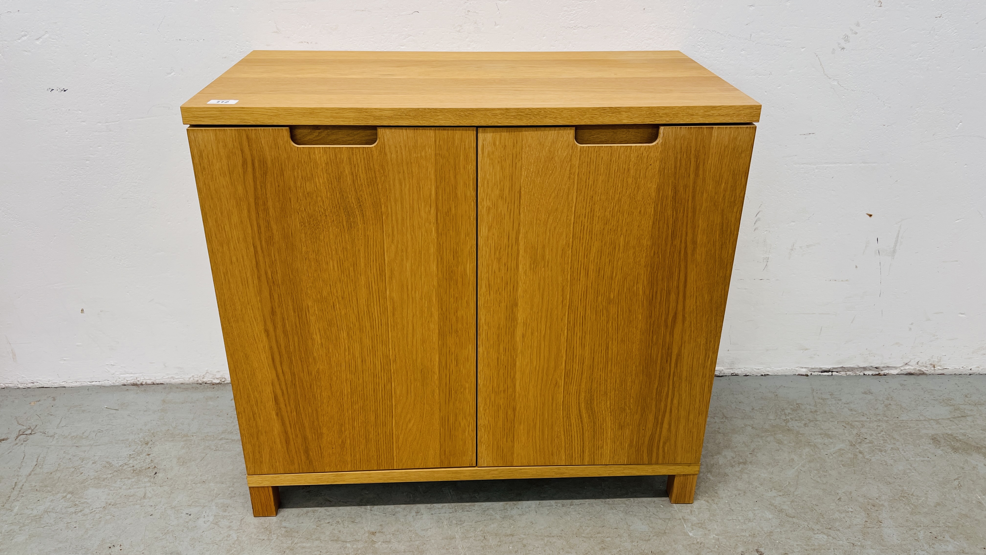 A MODERN LIGHT OAK FINISH TWO DOOR CABINET WITH SHELVED INTERIOR.