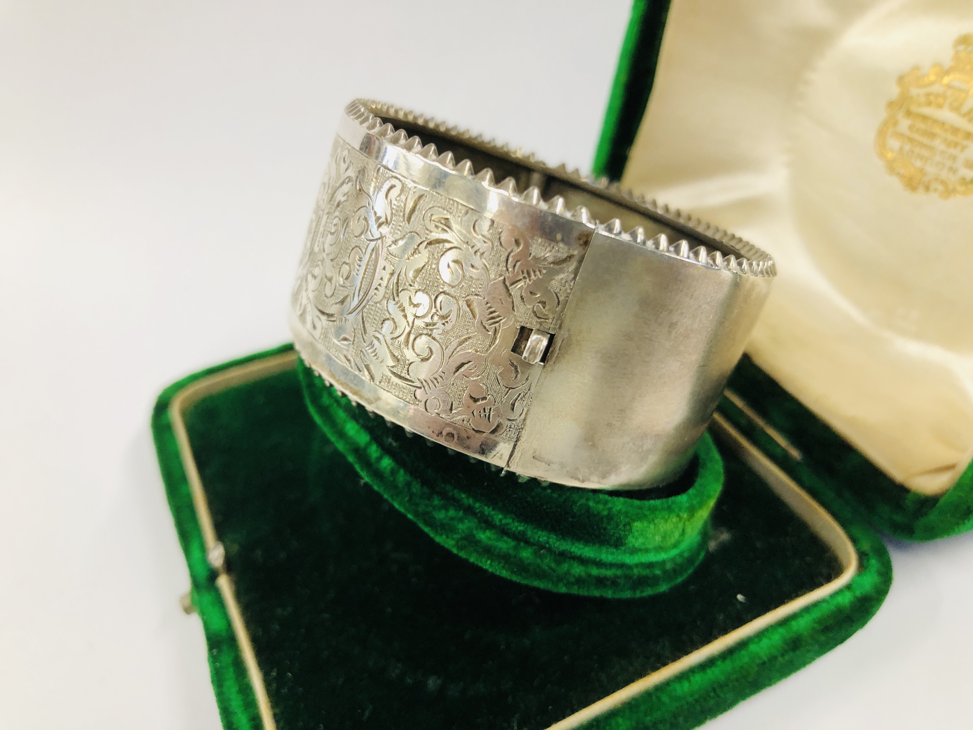 A VINTAGE WHITE METAL ENGRAVED HINGED BANGLE IN AN ANTIQUE GREEN VELVET BOX MARKED "THE ALEX CLARK" - Image 5 of 11