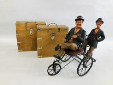 A PAIR OF HARDWOOD AND METAL BOUND BOXES ALONG WITH A LAUREL AND HARDY BICYCLE SCULPTURE.