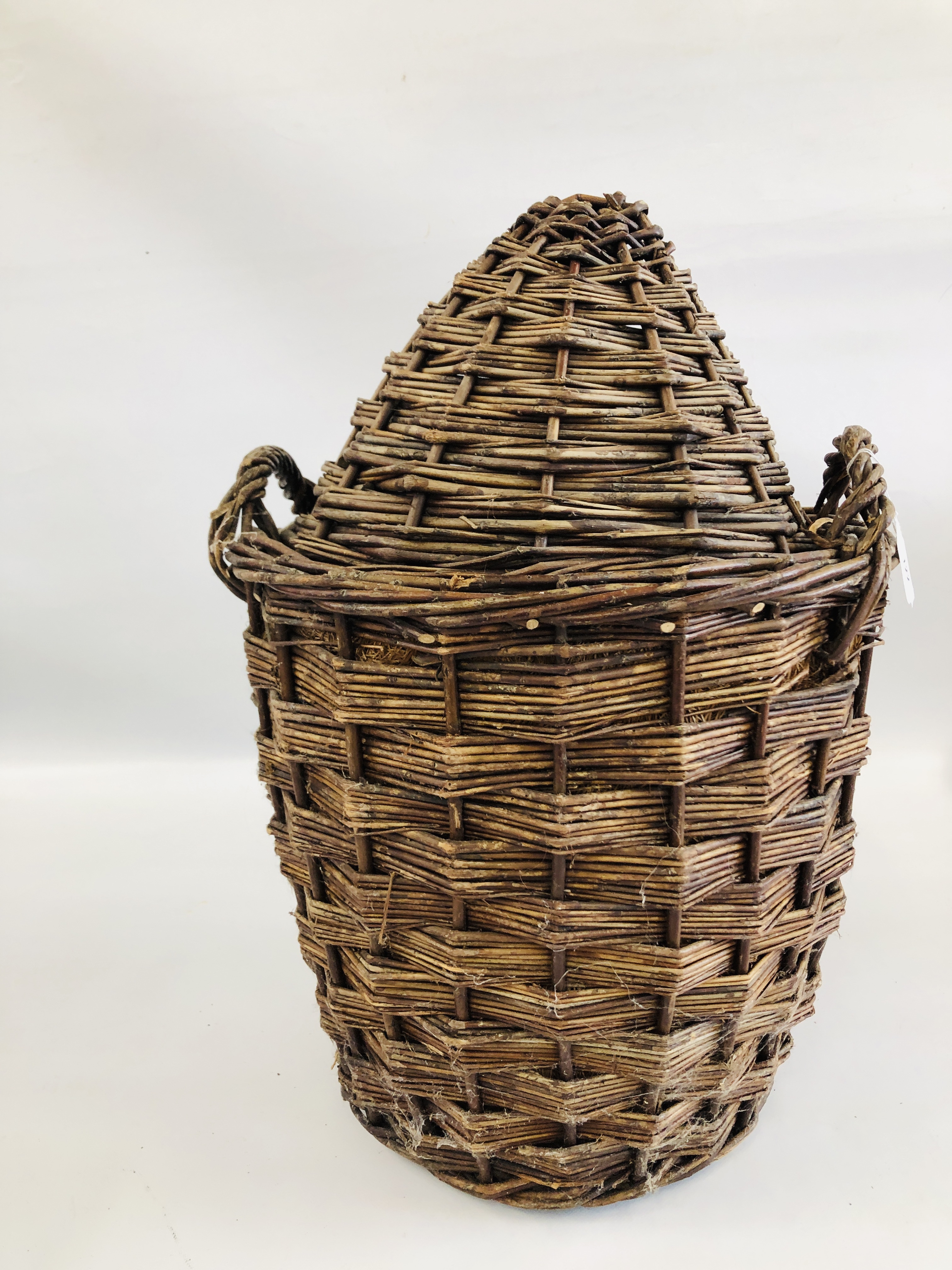 A VINTAGE GLASS DEMIJOHN IN ORIGINAL FITTED TWO HANDLED WICKER BASKET AND COVER - H 60CM.