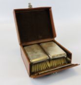 SILVER BACKED BRUSH AND COMB SET IN TAN LEATHER TRAVELLING CASE.