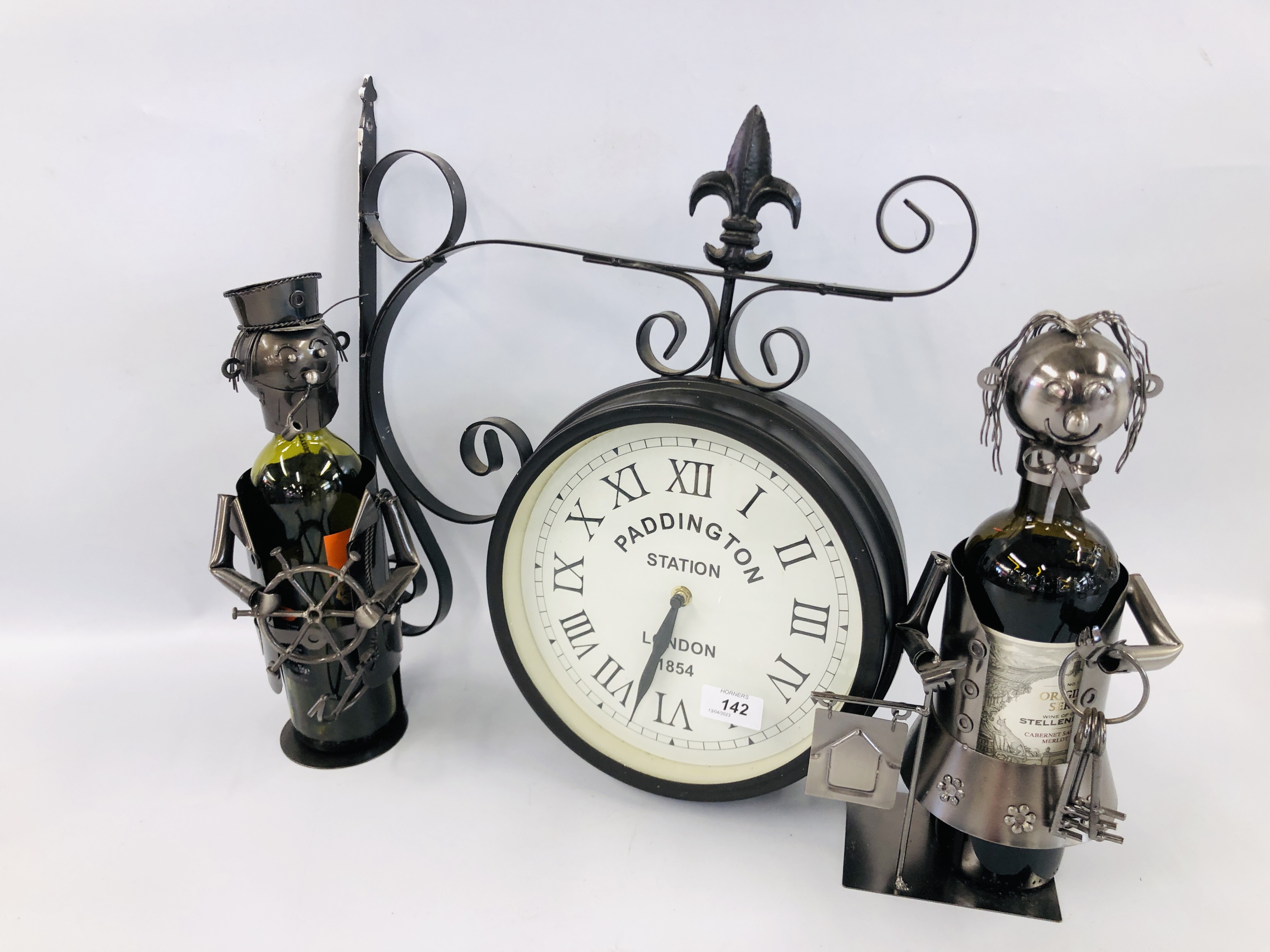 A REPRODUCTION GARDEN CLOCK ON BRACKET MOUNT AND TWO METAL CRAFT WINE BOTTLE HOLDERS (BOTTLES