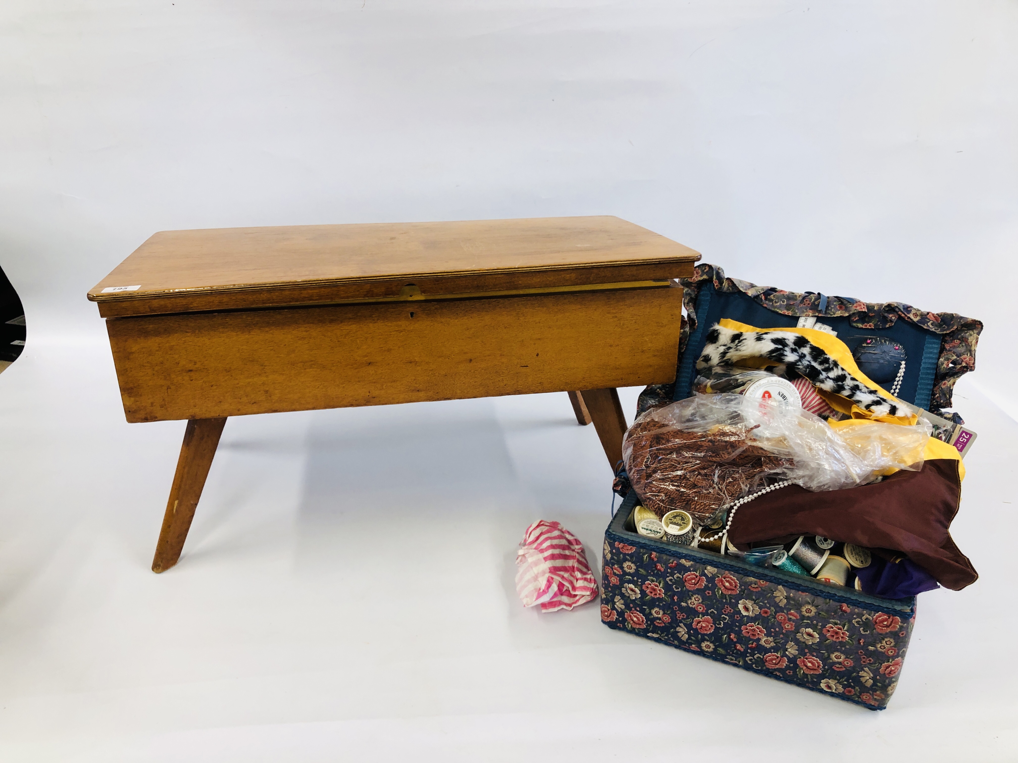 A MID CENTURY SPLAYED LEG WORK CHEST FILLED WITH SEWING ACCESSORIES AND FABRICS ALONG WITH A