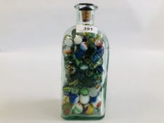 A GLASS BOTTLE CONTAINING A COLLECTION OF VARIOUS GLASS MARBLES.