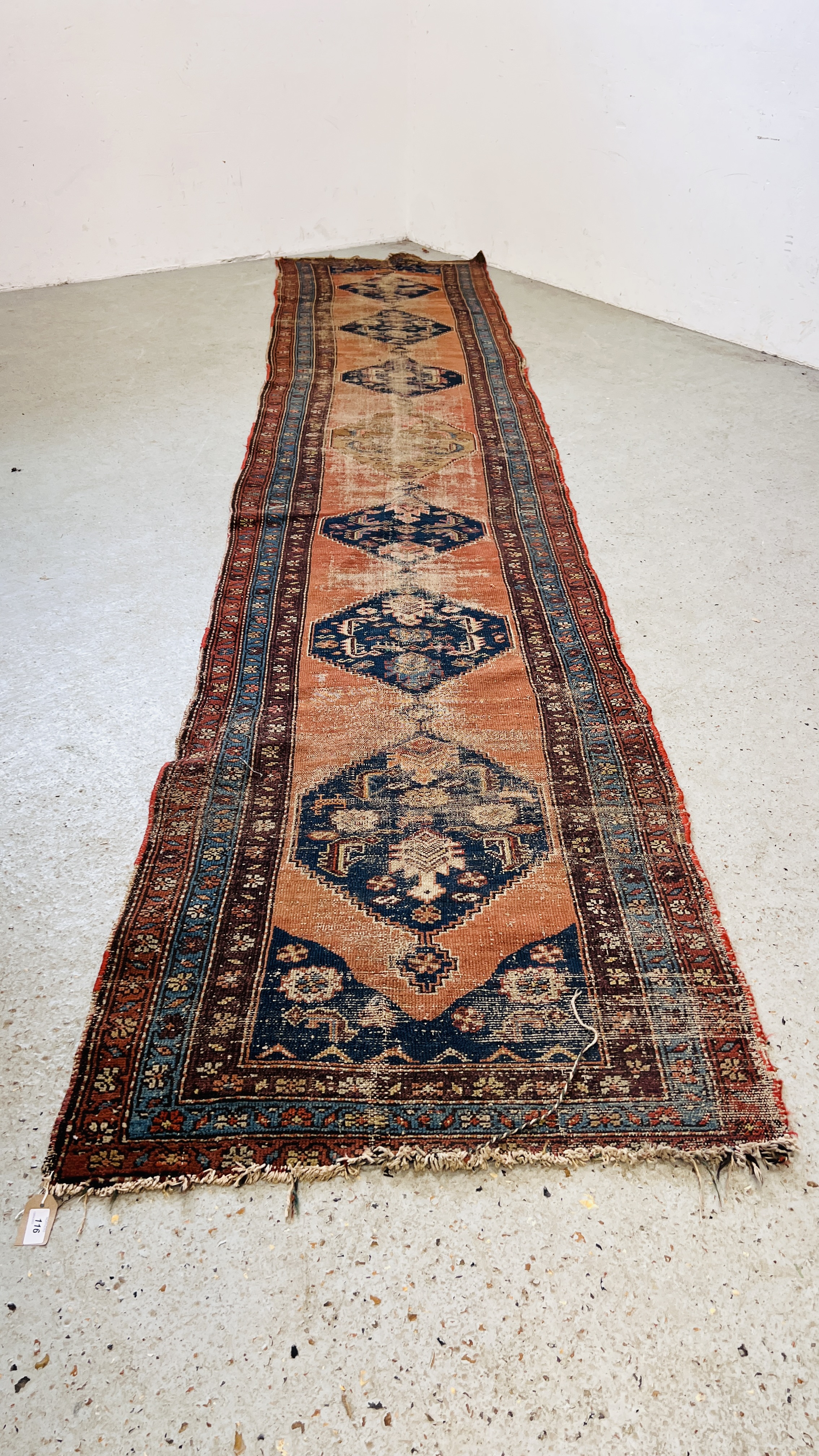 A TRADITIONAL CAUCASIAN RUNNER, THE CENTRAL LOZENGES ON A BRICK RED FIELD, WORN CONDITION.