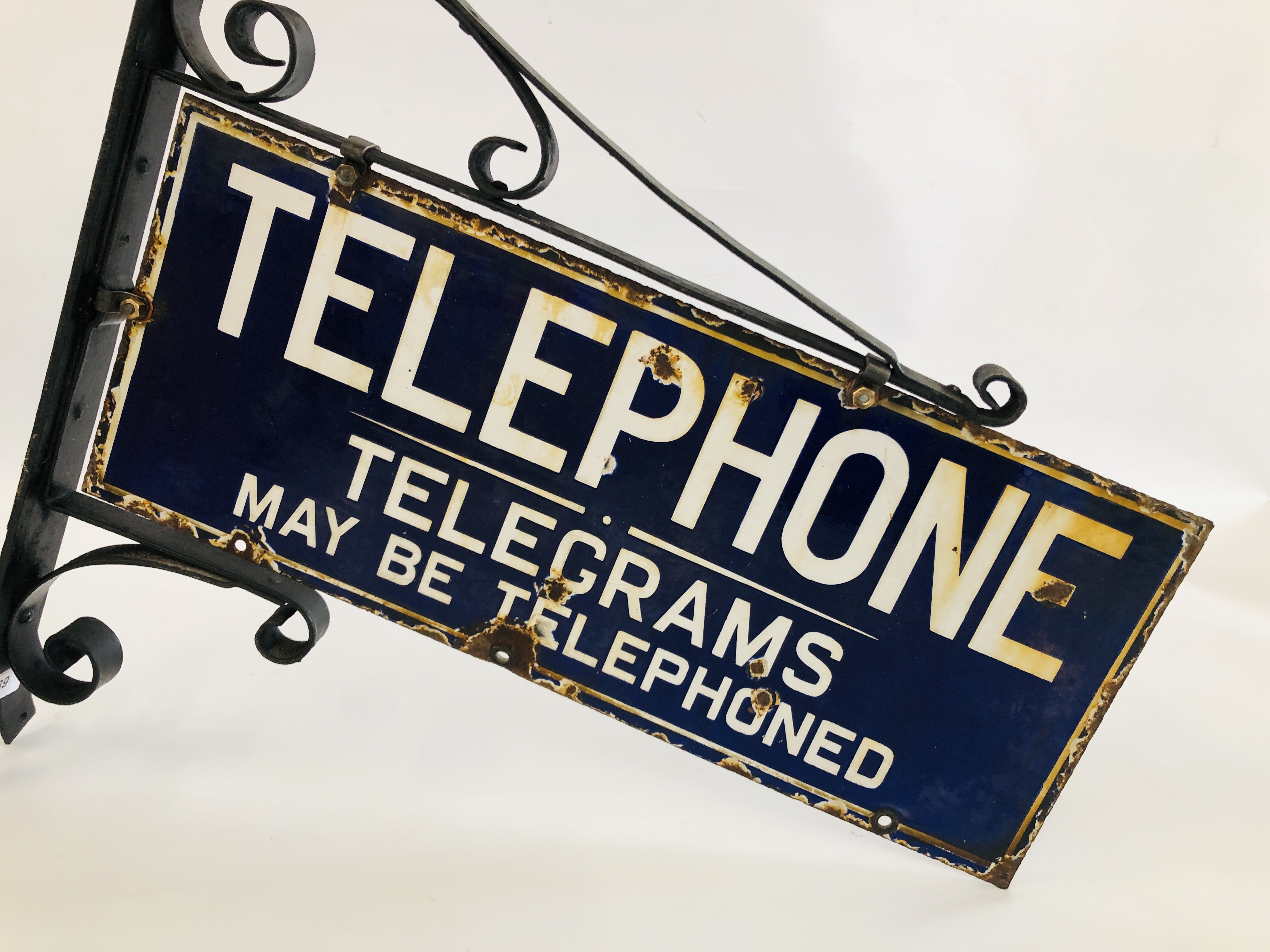 A VINTAGE ENAMELED TELEPHONE SIGN MOUNTED IN WALL BRACKET "TELEPHONE,