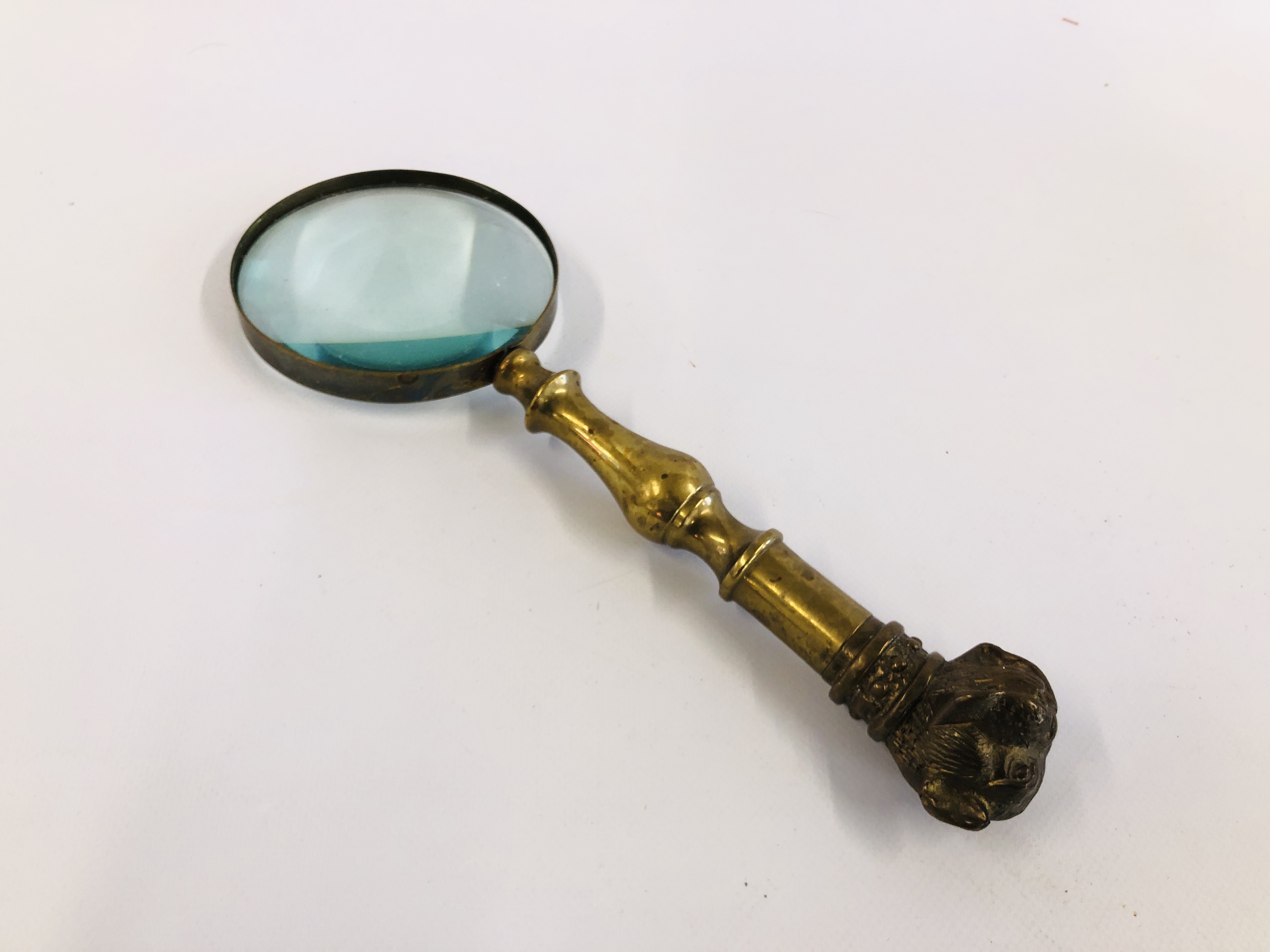 A VINTAGE BRASS MAGNIFYING GLASS, THE HANDLE HAVING SCREW TOP BULLDOG HEAD FIGURE.