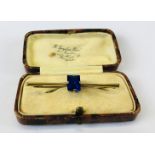 A 9CT GOLD BAR BROOCH SET WITH BAGUETTE BLUE STONE IN VINTAGE PRESENTATION BOX.