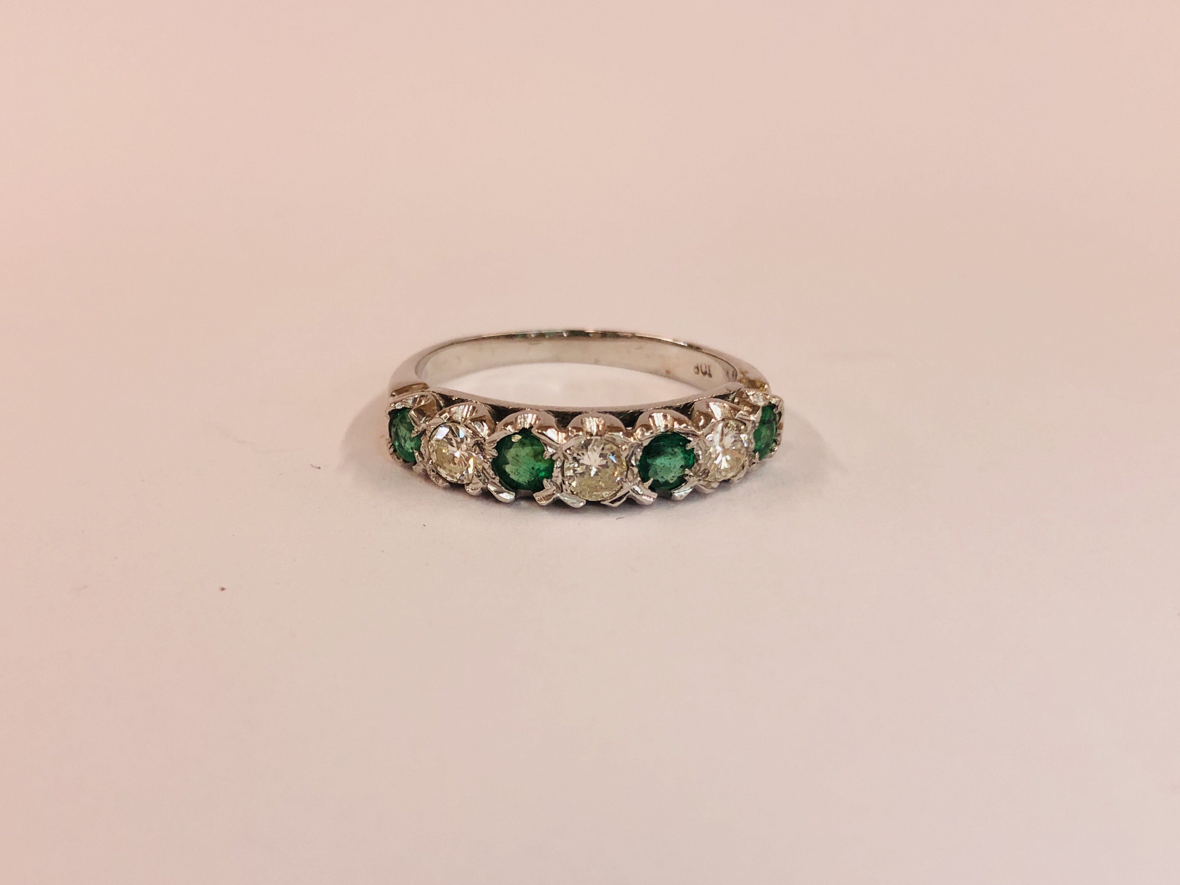 AN 18CT WHITE GOLD EMERALD AND DIAMOND HALF HOOP ETERNITY RING.