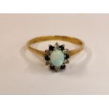 A 9CT GOLD RING SET WITH CENTRAL OVAL OPAL, SURROUNDED BY SMALLER DIAMONDS AND SAPPHIRES.