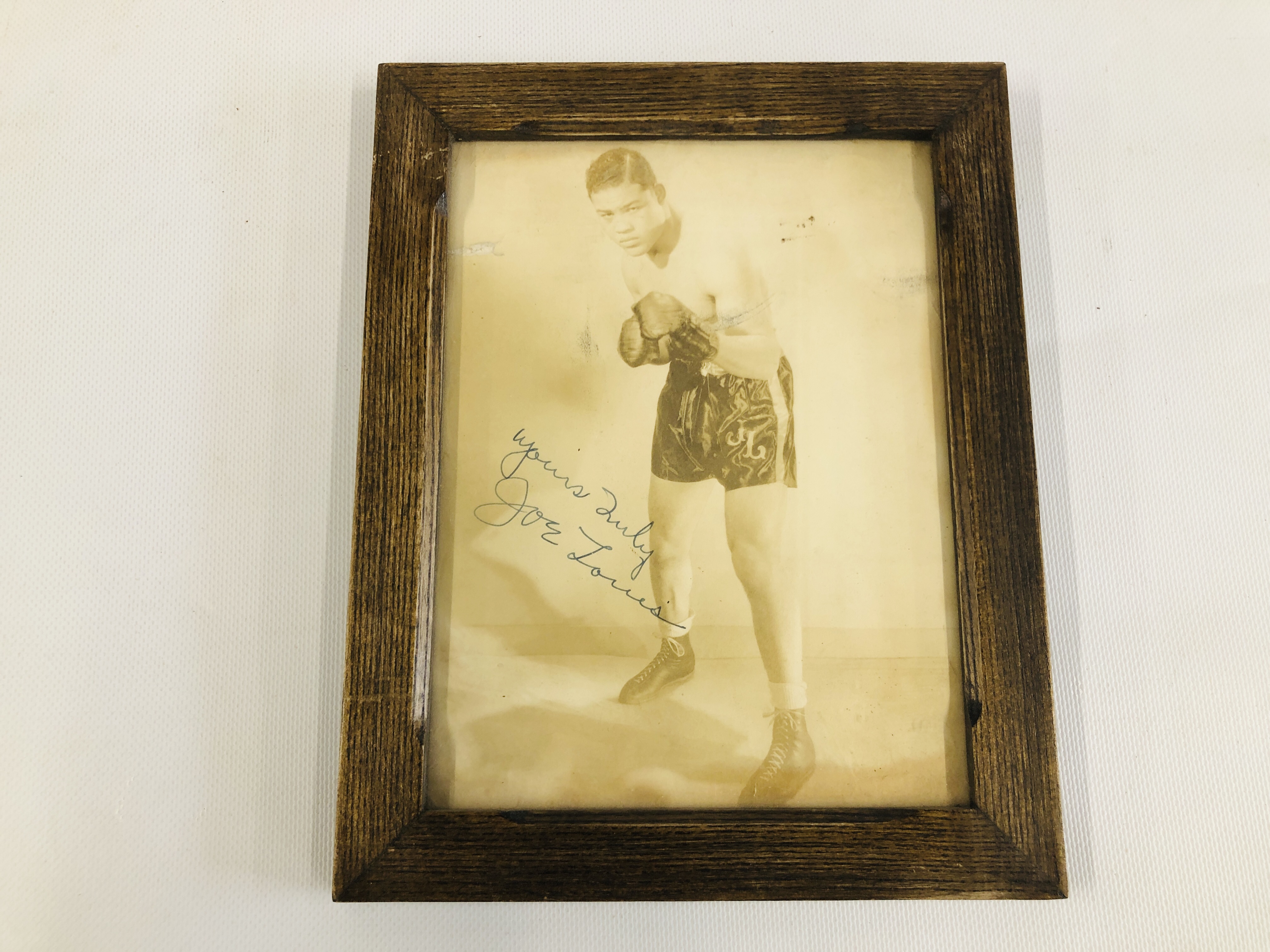 A FRAMED AND MOUNTED PHOTOGRAPH JOE LOUIS BEARING SIGNATURE JOE LOUIS - H 22CM X W 16.5CM.