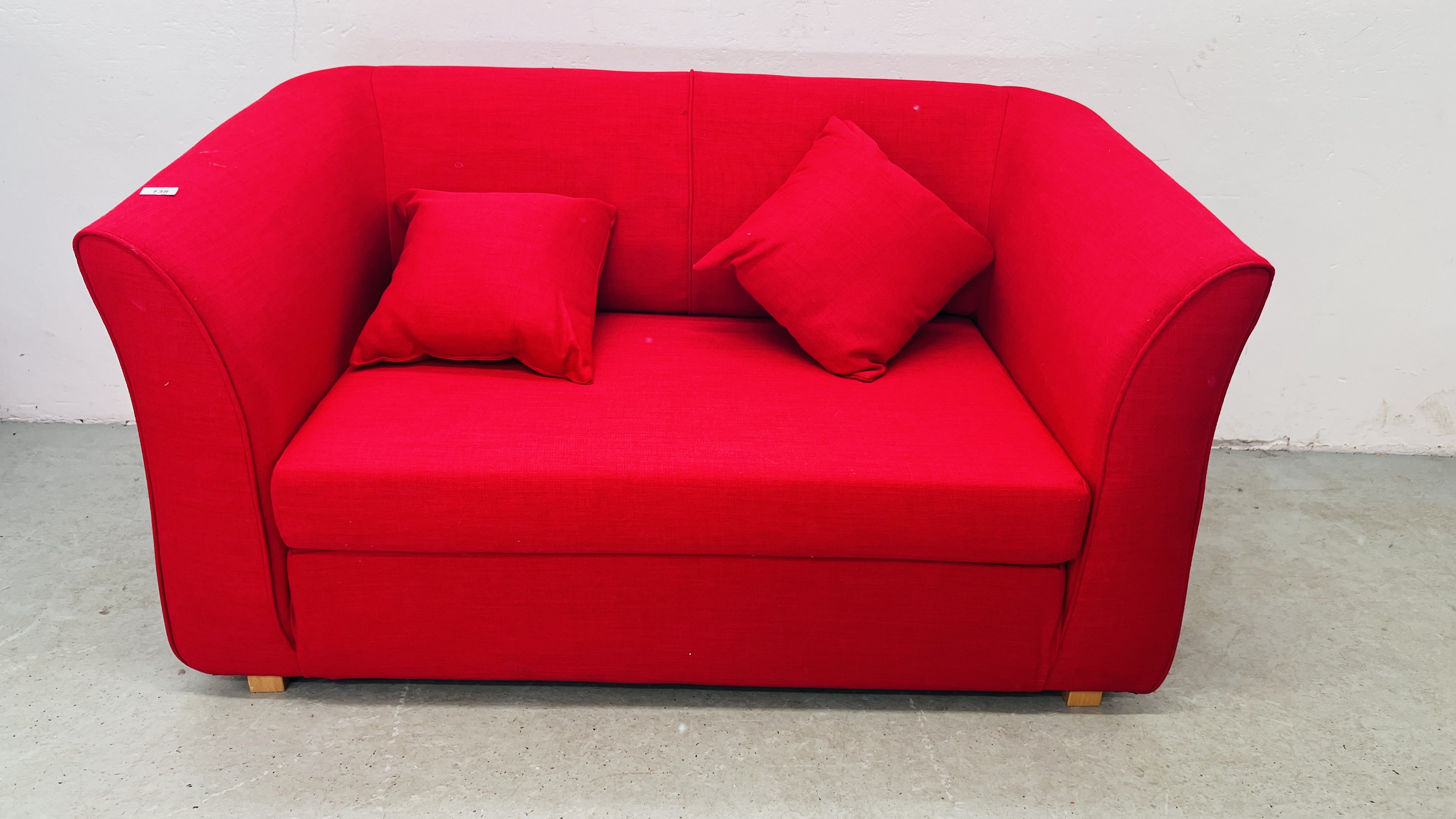 A MODERN RED FABRIC UPHOLSTERED TWO SEATER SOFA WITH MATCHING CUSHIONS.