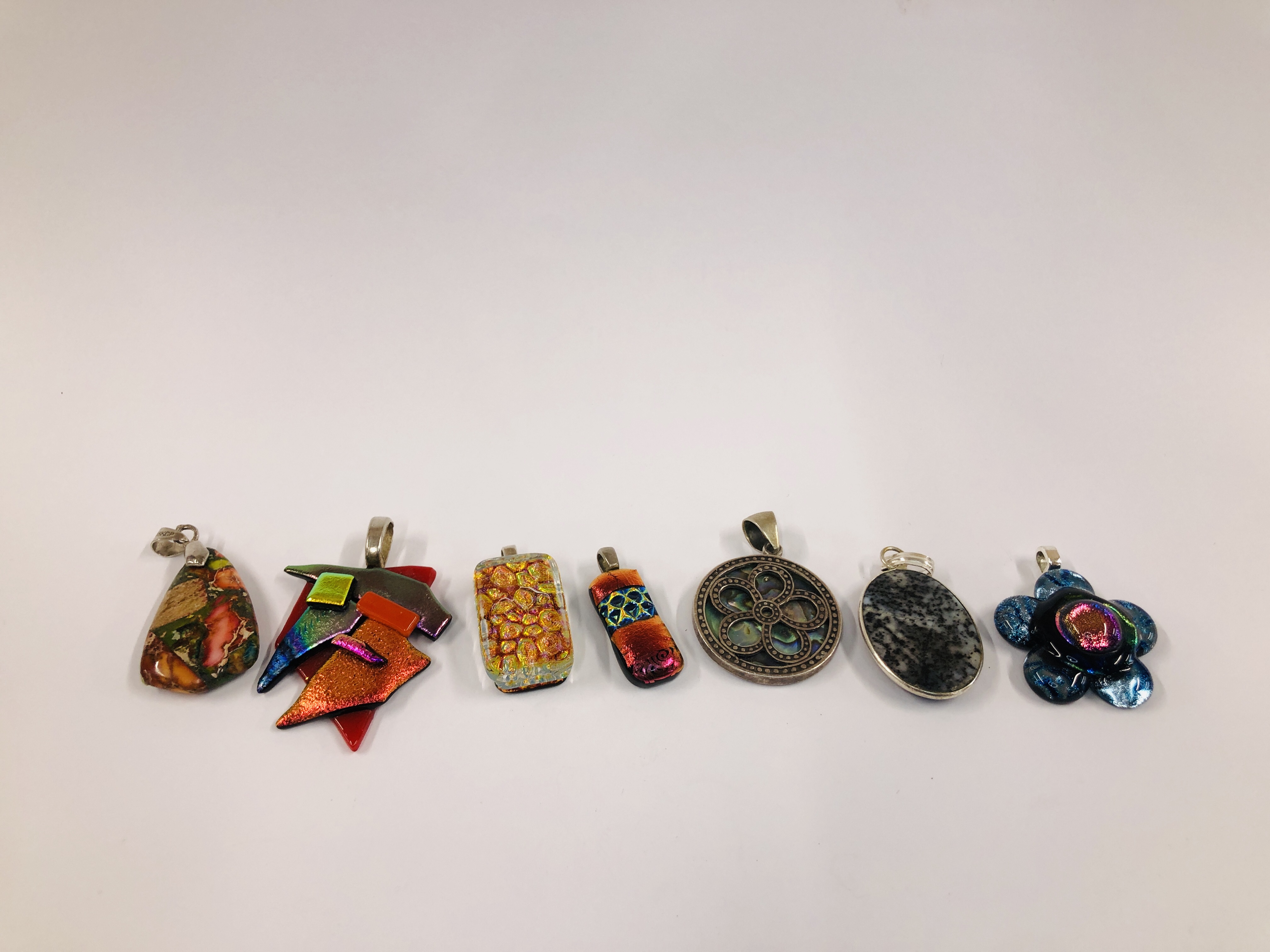 A GROUP OF 7 ASSORTED CONTEMPORARY PENDANTS TO INCLUDE SOME SILVER AND GLASS EXAMPLES.