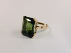AN UNMARKED YELLOW METAL RING SET WITH AN EMERALD CUT GREEN STONE (THE BAND CUT) H 1.6CM X W 1.2CM.