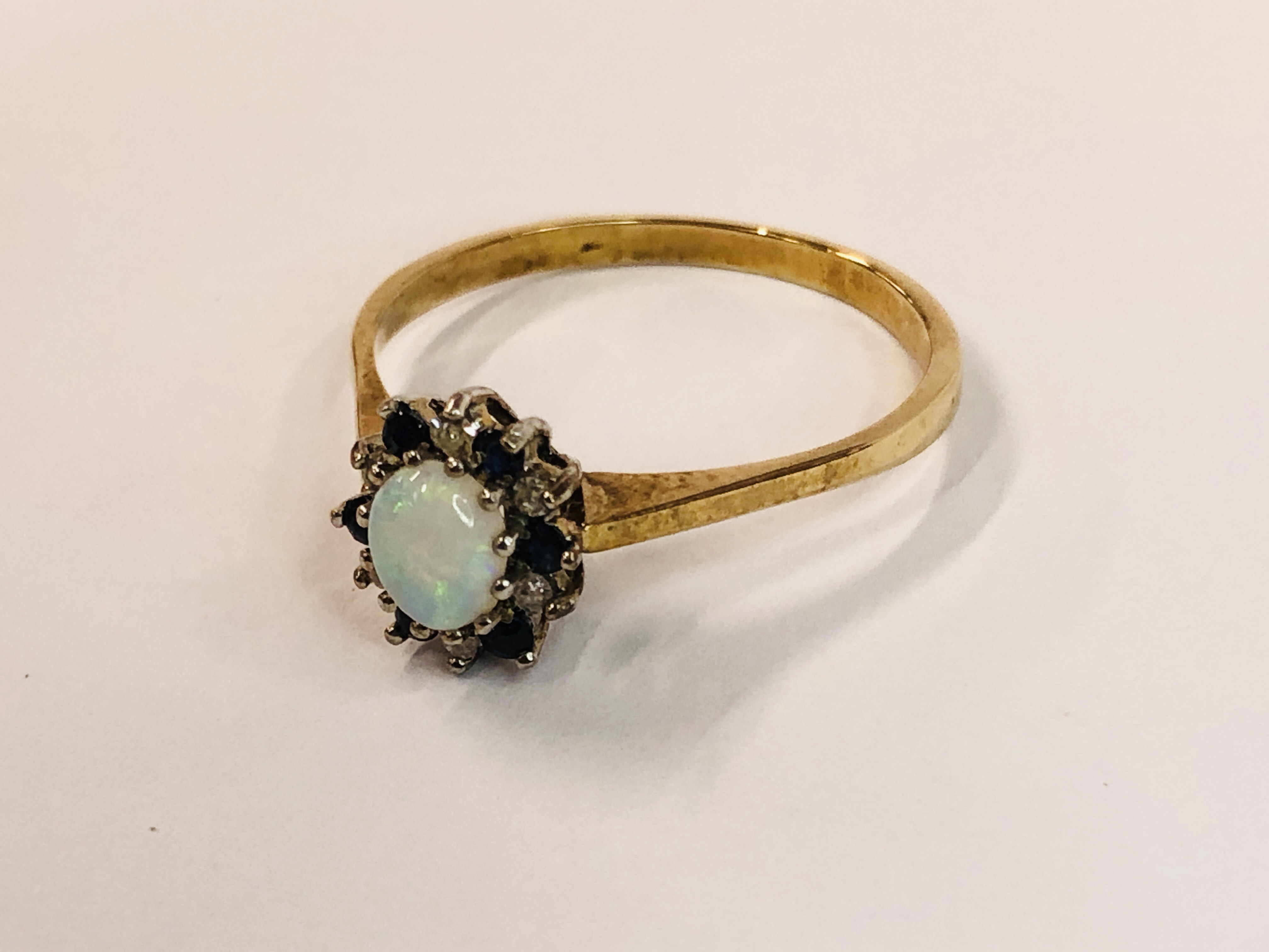 A 9CT GOLD RING SET WITH CENTRAL OVAL OPAL, SURROUNDED BY SMALLER DIAMONDS AND SAPPHIRES. - Image 3 of 9
