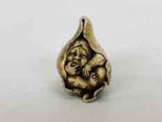 CARVED ANTLER NETSUKE STUDY OF BOY IN A PEACH SIGNED.