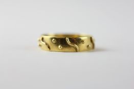 AN UNUSUAL 18CT GOLD WEDDING BAND WITH APPLIED RAISED DETAIL.