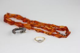 AN AMBER NECKLACE OF FACETED PEAR SHAPE BEADS ALONG WITH A LADIES RING MARKED 18CT SET (SOME