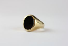 A 9CT GOLD ONYX SIGNET RING.