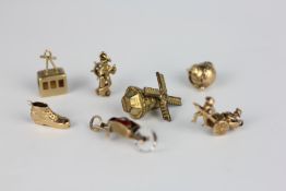 A GROUP OF SEVEN CHARMS TO INCLUDE TWO 9CT GOLD AND FIVE YELLOW METAL EXAMPLES.