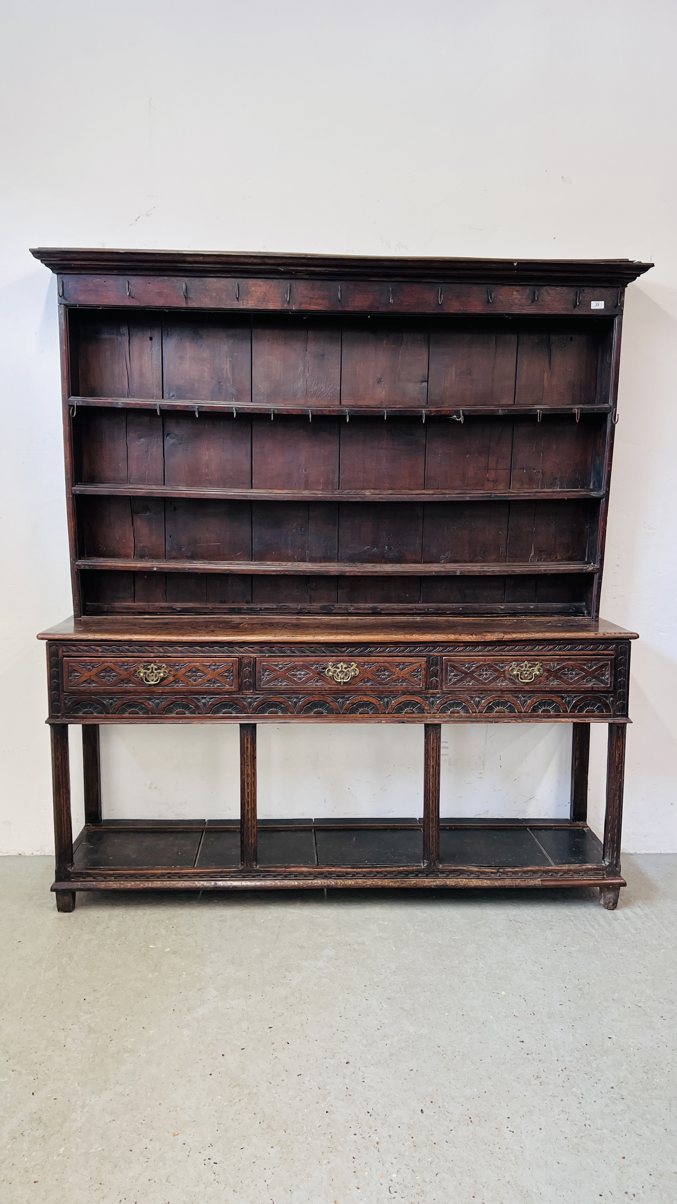 AN EARLY HEAVILY CARVED THREE DRAWER DRESSER BASE WITH ASSOCIATED DRESSER BACK, WIDTH 180CM.