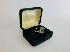 AN 18CT GOLD RING SET WITH A CENTRAL GREEN STONE SURROUNDED BY SMALLER DIAMONDS.