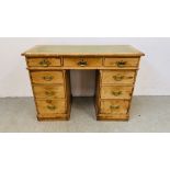 AN ANTIQUE WAXED PINE NINE DRAWER KNEEHOLE DESK WITH TOOLED LEATHER INSET TOP.