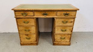 AN ANTIQUE WAXED PINE NINE DRAWER KNEEHOLE DESK WITH TOOLED LEATHER INSET TOP.